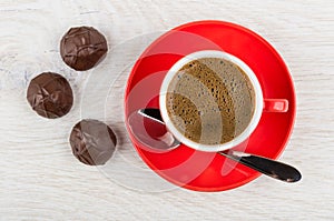 Coffee in red cup, spoon on saucer, chocolate candy