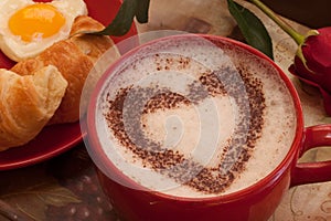 Coffee in red mug with hearth shape cocoa dust photo