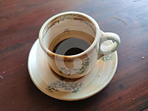 Coffee residue in a cup and saucer on a brown wooden table photo