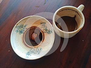 Coffee residue in a cup and saucer on a brown wooden table photo