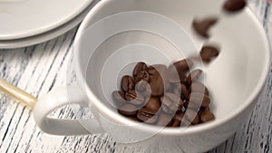 Coffee roasted arabica beans are poured into a white cup on the table.