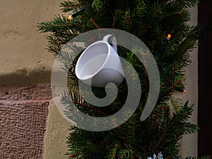 Coffee roasters shop in downtown with winter decor. Green natural fir tree branch with white cup lights on cafe facade