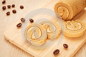 Coffee roll cake on wooden board and coffee beans