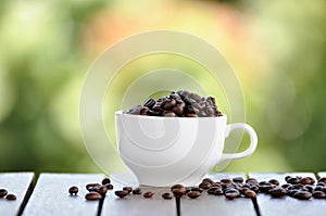 Coffee seeds with white cup and nice bokeh blur background.