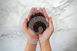 Coffee beans in hands, with marble background