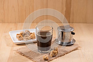 Coffee serve with almond candies on a wooden table.