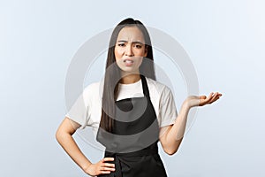 Coffee shop, small business and startup concept. Displeased and confused young asian waitress, barista or cafe owner in
