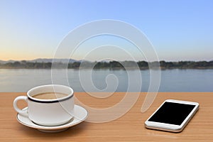 Coffee and smart phone on wooden table with nature background