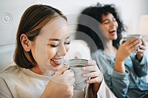 Coffee, smile and lesbian couple on bed in conversation for bonding and relaxing together. Happy, rest and interracial