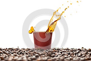 Coffee splash in brown disposable paper cup with coffee beans isolated on white.