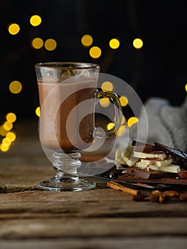 Coffee table. Glass cup coffee latte, chocolate, sweets, decor. Golden lights in the background. Wooden structure. Christmas, New