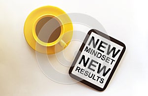 Coffee and tablet with text New Mindset New Results on the white background