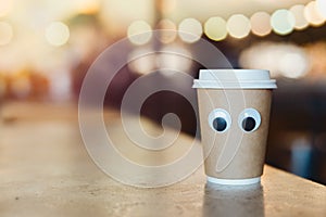 Coffee takeaway cup with cartoon eyes in cafe. Concept of hospitable cafe