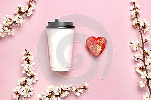 Coffee or tea paper cup, heart-shaped macaroon cakes, spring branches of white flowers on pink background top view flat