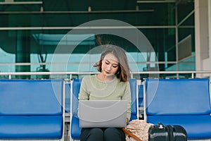 Coffee time. Attractive woman sitting in airport lounge, drinking coffee and working on laptop