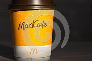 Coffee to go of McDonald`s with the inscription Maccafe in Russian stick with sugar on the table with a napkin and a straw. Fast