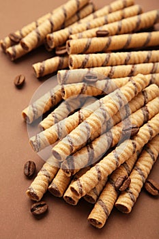 Coffee wafer stick roll with coffee cream on brown background. Vertical photo