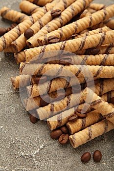 Coffee wafer stick roll with coffee cream on grey background. Vertical photo