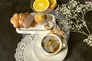 Coffee in white cup dishes with cakes,saucer with orange slices