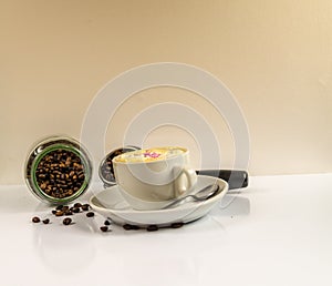 Coffee in a white cup with a fallen jar of coffee beans and port