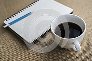 Coffee in white cup with Journal book and pencil