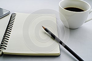 Coffee in white cup with Journal book and pencil