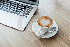 Coffee in white cup with laptop on table in office