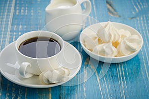 coffee in a white cup and meringue on a blue background/coffee in a white cup and meringue