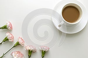 Coffee in white cup with pink and white carnation flowers