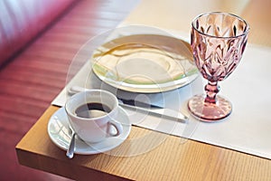 Coffee in white cup and saucer on table in cafe