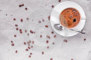 Coffee in a white cup, spoon and saucer on a concrete background