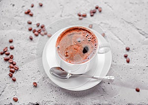 Coffee in a white cup, spoon and saucer on a concrete background