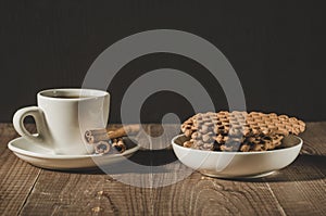 coffee in a white cup with sticks of cinnamon and cookies/coffee in a white cup with sticks of cinnamon and cookies on a wooden t