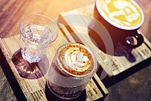 Coffee on the wooden table with latte art and color filter vintage
