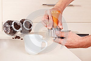 Coffeemaker presses coffee tablet in holder with tamper on table