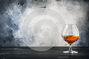 Cognac or brandy in wine glass, gray stone bar counter background, selective focus