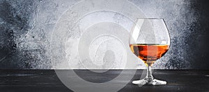 Cognac in a glass, gray background, long banner with copy space