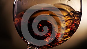 Cognac is rotated in a glass. On dark background.