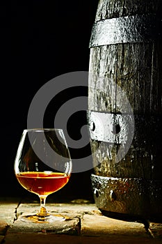 Cognac snifter and an old oak barrel