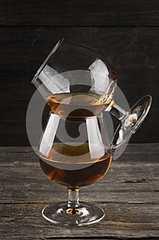 Cognac in two glasses on a dark wooden background