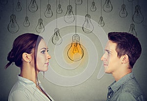 Cognitive skills ability concept, male vs female. Man and woman looking at bright light bulb photo