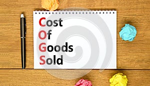 COGS cost of goods sold symbol. Concept words COGS cost of goods sold on white note on beautiful wooden background. Business COGS