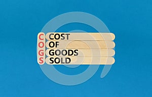 COGS cost of goods sold symbol. Concept words COGS cost of goods sold on wooden stick on beautiful blue background. Business COGS