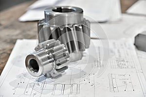 A cogwheel made on a gear cutting machine lies on the technical drawings