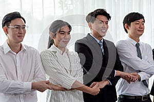 Cohesive office workers holding hand in line to promote harmony in workplace.