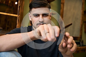 Coiffeur showing scissors while sitting at his workplace in barbershop photo