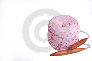 A coil of large knitted yarn of peach color with 20 mm circular bamboo needles on white background, isolation, copy space