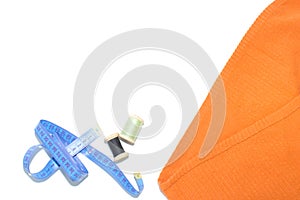 Coil with thread, scissors and ruler on a piece with a bright cloth, on a white background