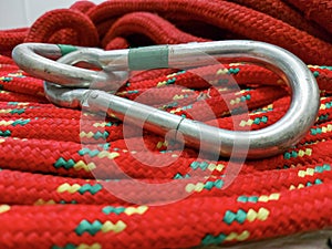 Coiled climbing rope and steel carabiner. Mountain climbing equipment: carbine, harness, brakes, quickdraws, self