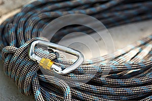 Coiled climbing rope and steel carabiner. Mountain climbing equipment: harness, brakes, quickdraws, self-insurance, belay device e